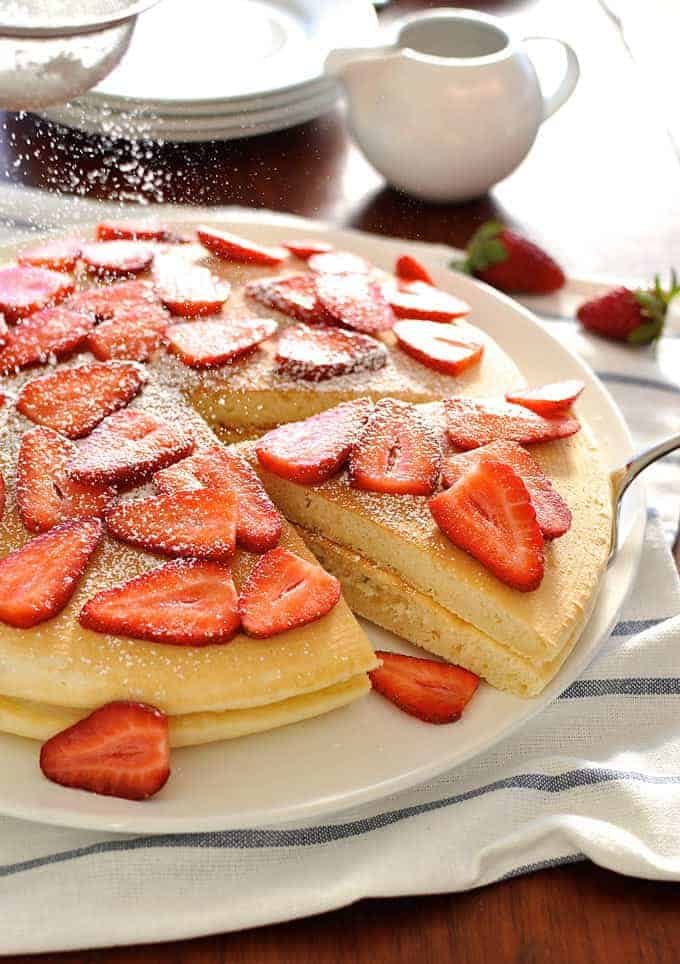 Giant pancake topped with strawberries, sprinkled with icing sugar
