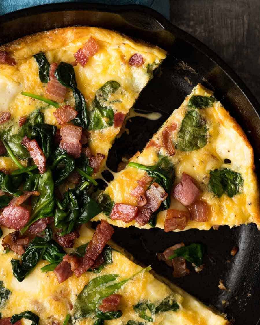 Overhead photo of Frittata with Bacon and Spinach in a black skillet, fresh out of the oven