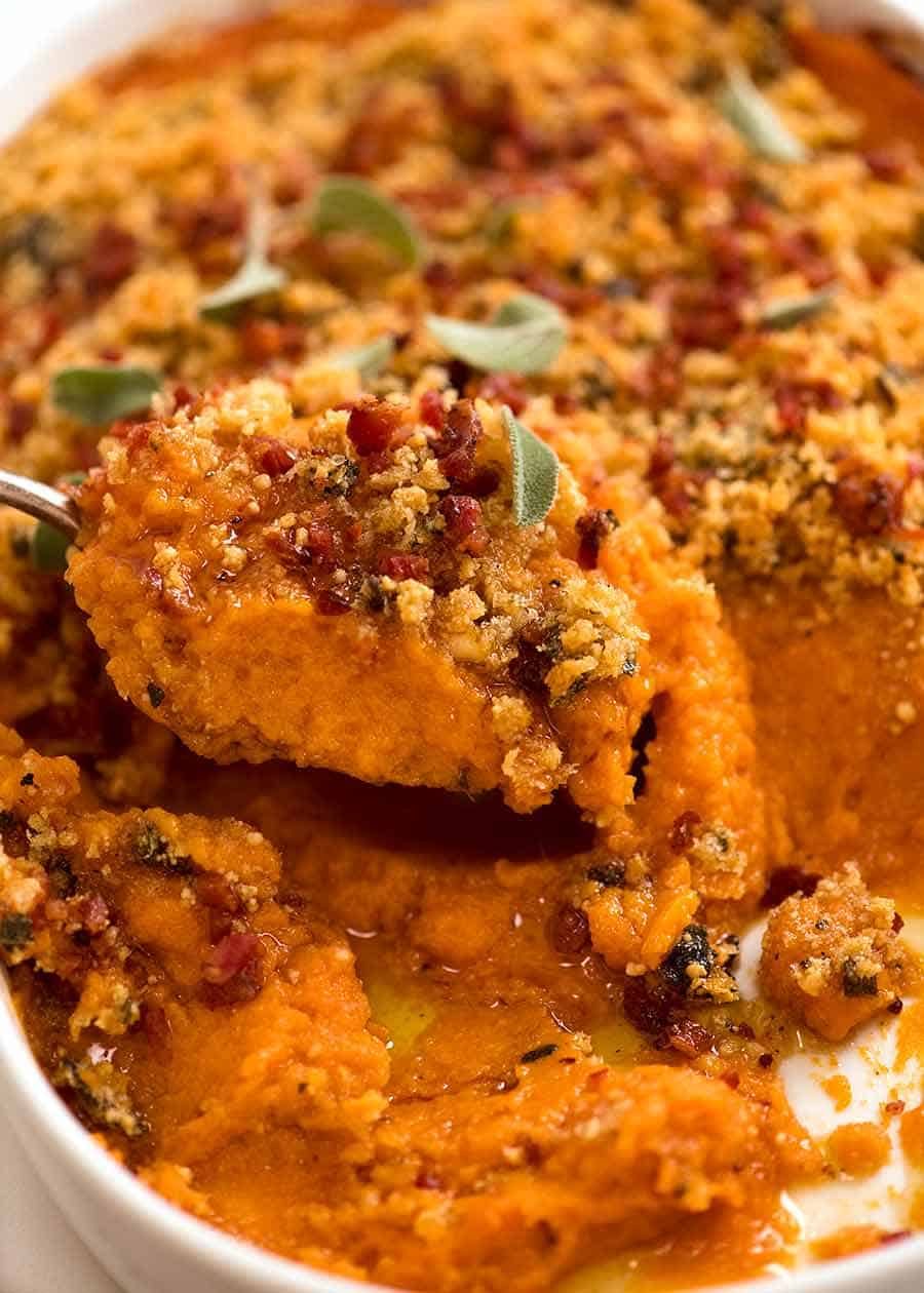 Close up of spoon scooping Browned Butter Sweet Potato Casserole from baking dish