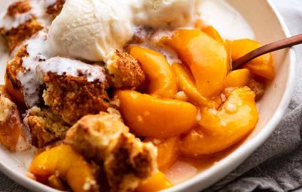 Peach Cobbler in a bowl topped with vanilla ice cream